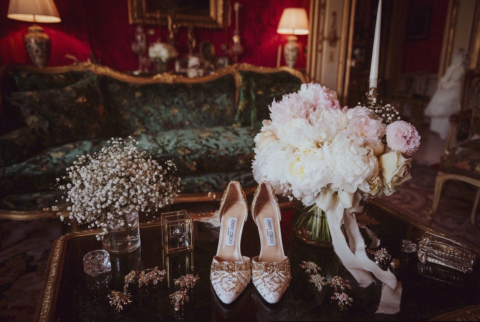 Elegant wedding details featuring embellished shoes, a bouquet of peonies, and delicate decorations on a lavish table.