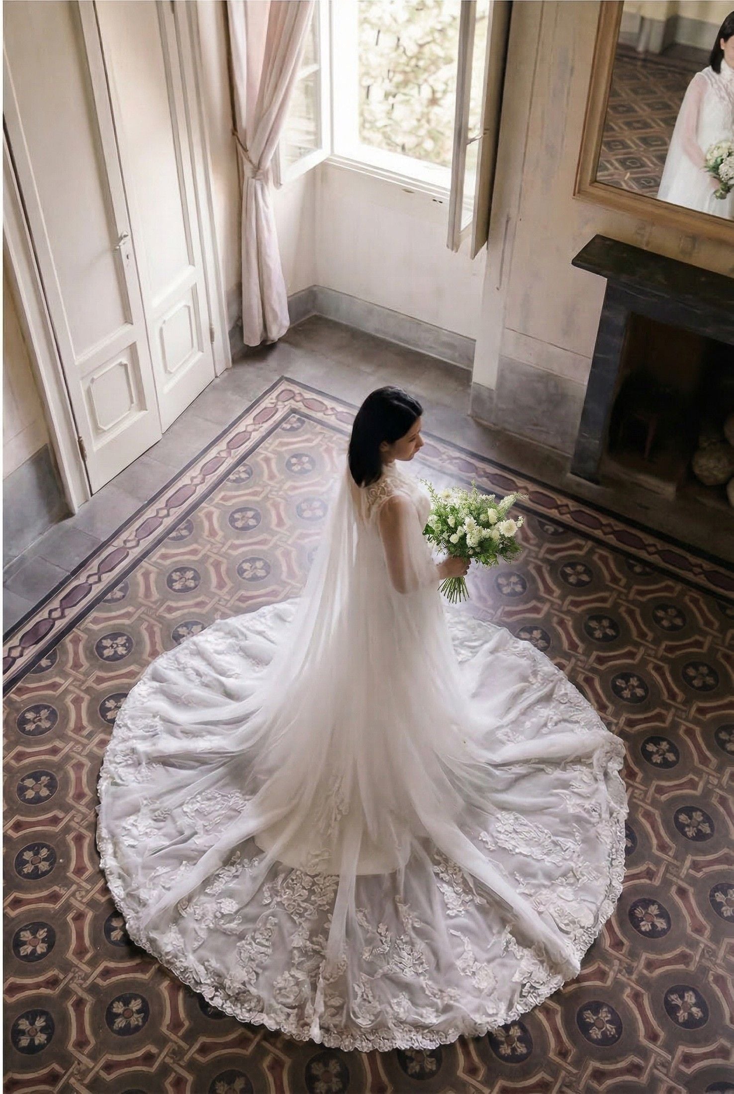 A bride in a flowing white gown stands gracefully in a sunlit room, holding a bouquet, with elegant decor around her.