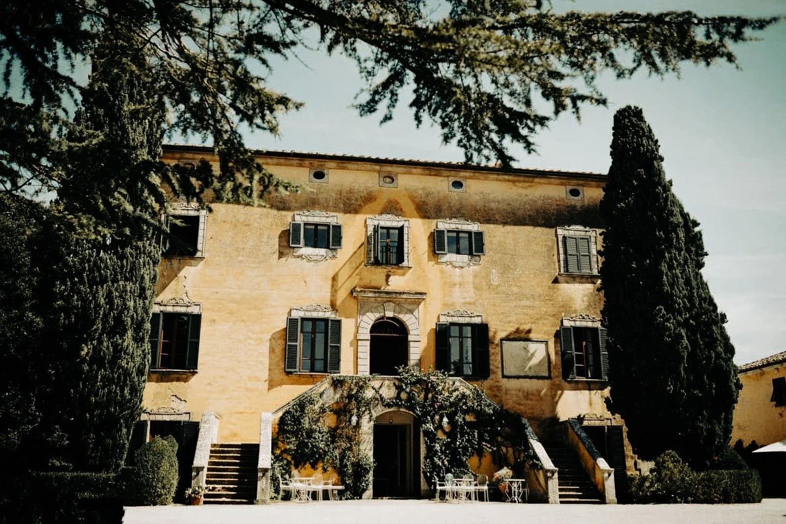 Historic villa surrounded by lush greenery and elegant landscaping, featuring arched entrance and ornate windows.