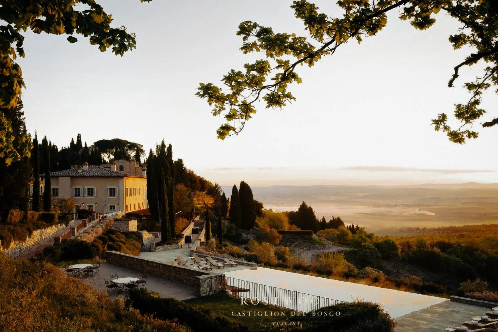 Sunrise over a Tuscan villa, overlooking lush hills and a tranquil landscape, with a swimming pool inviting relaxation.